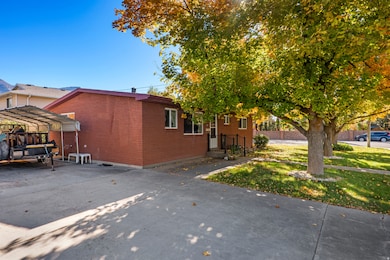 View of side of property featuring a yard, a carport, brick siding, and concrete driveway