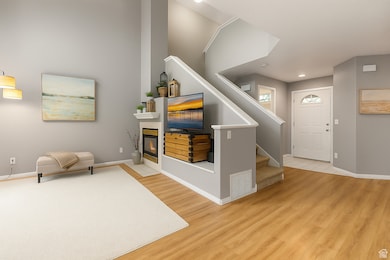 Foyer entrance with light wood-type flooring, a tiled fireplace in the family room with vaulted ceilings and a stairway