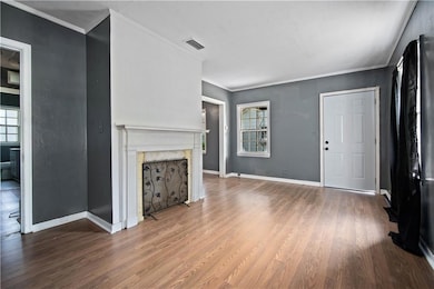 Unfurnished living room featuring a fireplace, wood finished floors, crown molding, and baseboards