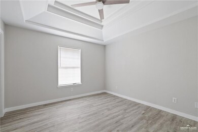 Empty room featuring a raised ceiling, wood finished floors, and ceiling fan