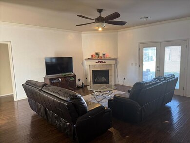 Living room featuring crown molding, a fireplace, french doors, dark wood-style floors, and a ceiling fan