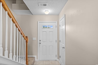 Foyer featuring a textured ceiling, stairway, and light tile patterned floors