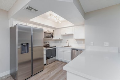 Kitchen with white cabinets, appliances with stain