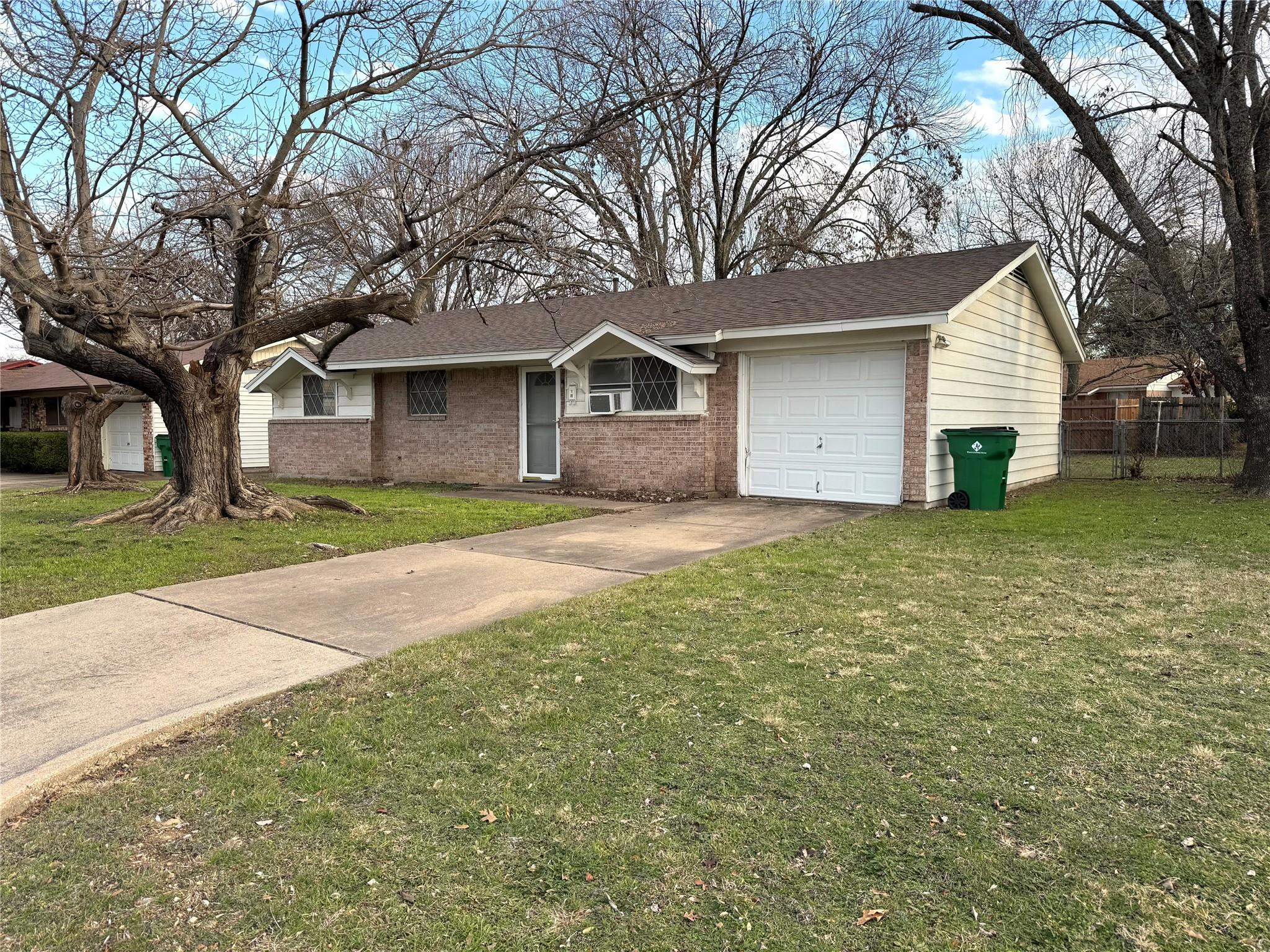 Single story home with a garage and a front lawn