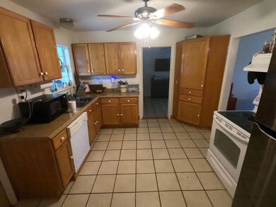 Kitchen with white appliances, ceiling fan, range