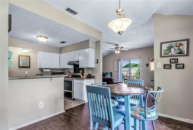 Kitchen with white electric range, kitchen peninsula, light stone countertops, dark hardwood / wood-style flooring, and white cabinetry