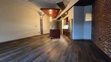 Unfurnished living room with brick wall, sink, dar