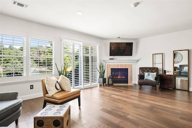 Living room with a tiled fireplace, wood finished floors, and recessed lighting