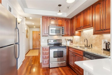 A view of the range/oven, microwave, refrigerator, and gorgeous wood flooring.