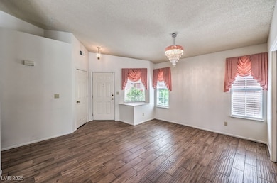 Empty room with a textured ceiling, a chandelier,