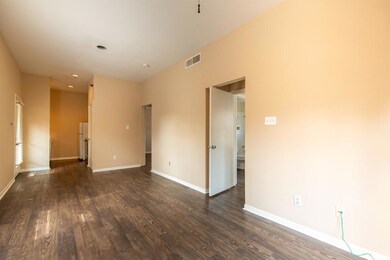 Empty room with dark wood-type flooring and baseboards