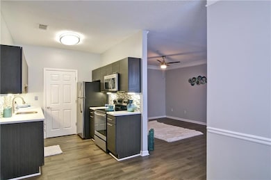 Kitchen featuring backsplash, ceiling fan, stainless steel appliances, wood-type flooring, and sink