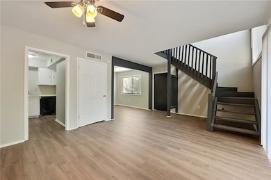 * Spacious living room featuring light wood-style flooring, stairs, and a ceiling fan