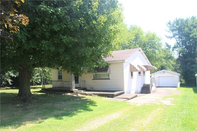 View of front of property featuring an outbuilding, driveway, a front yard, and a detached garage