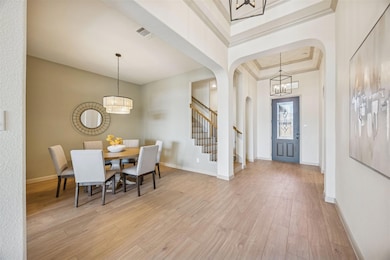 Entryway with a chandelier, a tray ceiling, arched walkways, light wood finished floors, and stairway