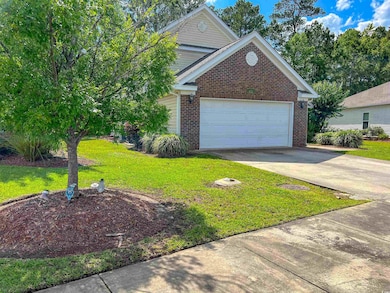 Traditional home with brick siding, a front yard, driveway, and a garage