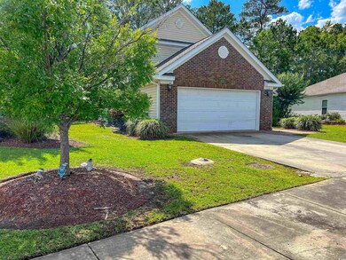 Traditional home with brick siding, a front yard, driveway, and a garage