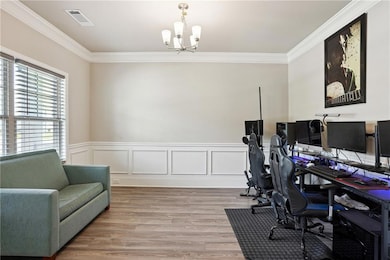 Home office with a chandelier, ornamental molding, wainscoting, and light wood-type flooring