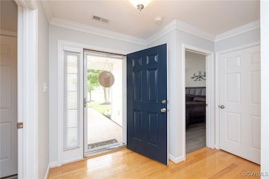 Foyer with storm door, wood flooring and crown mol