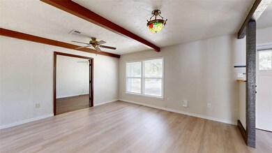Spare room with beamed ceiling, light wood-style floors, a textured wall, a textured ceiling, and a ceiling fan