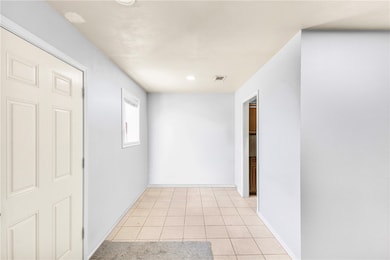 Hallway featuring light tile patterned floors and baseboards