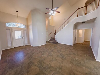 Foyer featuring high vaulted ceiling, a ceiling fan, and stairway