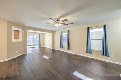Empty room featuring ceiling fan, dark LVP finishe