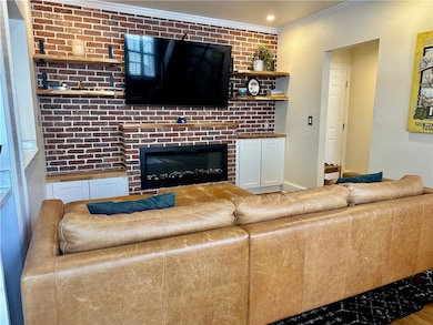 Living room featuring crown molding and a brick fireplace