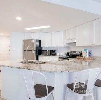 Kitchen with white cabinetry, stainless steel appliances, a kitchen bar, and recessed lighting