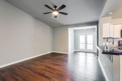 Unfurnished living room featuring dark wood-style floors, french doors, and a ceiling fan