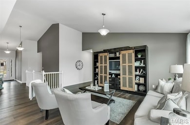 Living area with dark wood-style floors and lofted ceiling