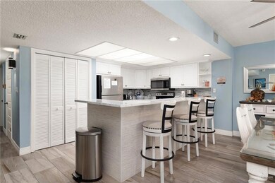 Kitchen with stainless steel appliances, a textured ceiling, open shelves, a peninsula, and white cabinetry