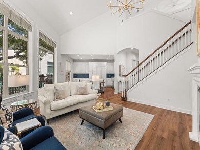 Living room with wood finished floors, recessed lighting, a chandelier, stairs, and arched walkways