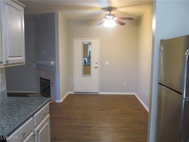 Kitchen featuring freestanding refrigerator, dark wood finished floors, a ceiling fan, and a tile fireplace