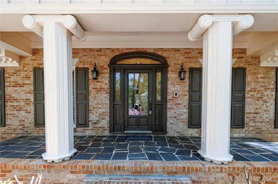 Property entrance with covered porch and brick siding