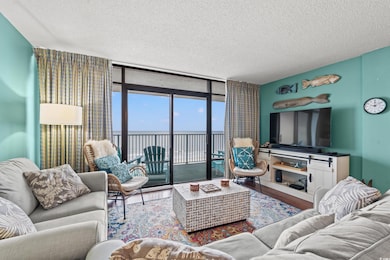 Living room featuring wood-type flooring, a textured ceiling, and a wall of windows
