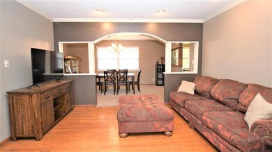 Living Room With Wood Floors And Arched Wall Looking Into Dining Room