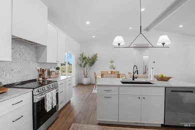Kitchen with stainless steel appliances, backsplash, white cabinetry, pendant lighting, and wood finished floors