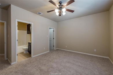 Unfurnished bedroom featuring visible vents, light carpet, baseboards, and ensuite bathroom