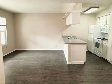 Kitchen with baseboards, white appliances, a sink