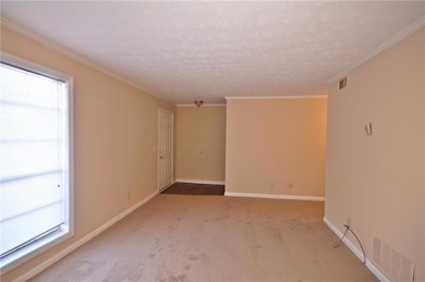 Empty room featuring a textured ceiling, crown mol