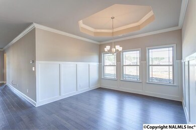 This open dining room boasts a tray ceiling, gleaming chandelier, and beautiful wainscoting.