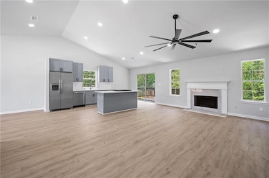 Unfurnished living room featuring light wood-style floors, a fireplace, plenty of natural light, ceiling fan, and recessed lighting