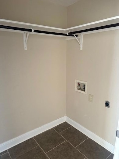 Washroom featuring dark tile patterned flooring, hookup for a washing machine, and hookup for an electric dryer