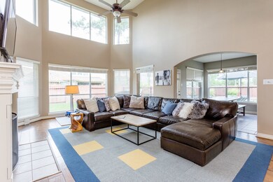 The great light-filled family room features custom paints, high ceilings, gas log fireplace, bookshelves, designer ceiling fan and a flat screen television.
