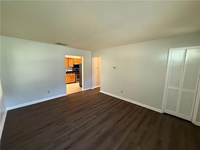 Unfurnished living room with a textured ceiling and dark wood-style flooring