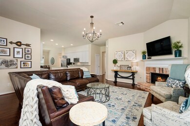Spacious living room overlooks the wooded park in the back of the home, and features plantation shutters and a brick fireplace.