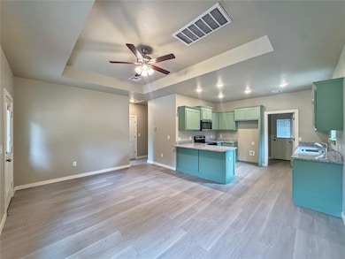 Kitchen area featuring mint cabinetry, granite countertops, modern lighting, and wood-style flooring. Note: Photos are of a similar home by the builder.