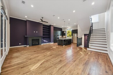 The heart of the home shines in this open-concept living and kitchen area, perfect for entertaining. Rich hardwood floors flow seamlessly throughout, complemented by a cozy fireplace and custom built-ins. The chef’s kitchen features a large island, modern cabinetry, and stainless steel appliances—all framed by abundant natural light and easy access to the balcony for indoor-outdoor living.