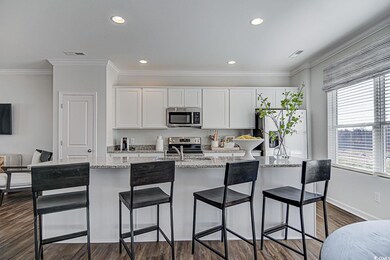 Kitchen with visible vents, dark wood finished floors, a center island with sink, white cabinets, and stainless steel appliances